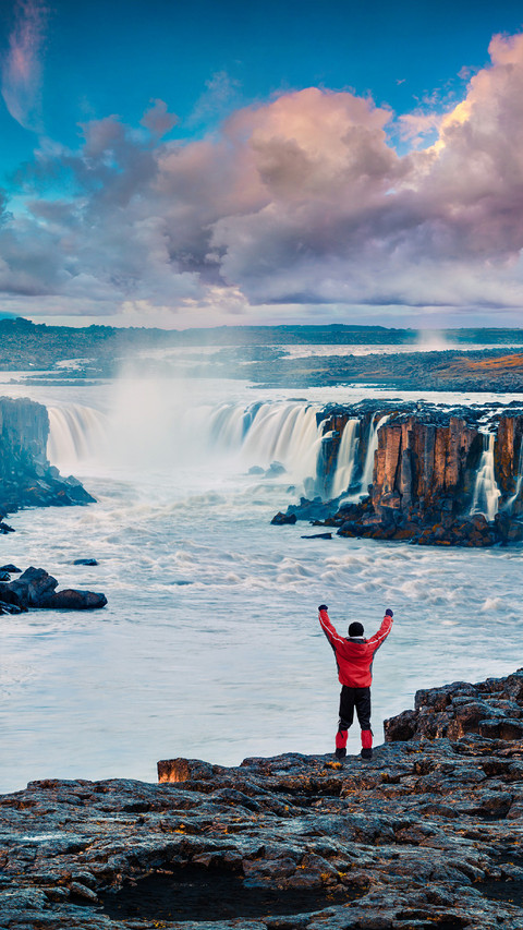 Man Standing on The Edge of The Cliff Facing The Waterfall screenshot
