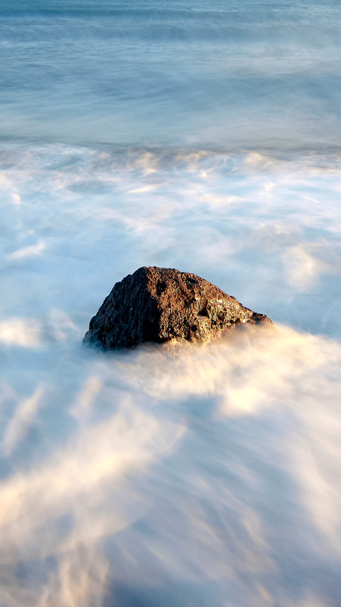 A beautiful view of sea waves crashing on beach rocks screenshot