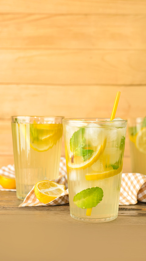 Glasses of tasty cold lemonade on wooden background screenshot