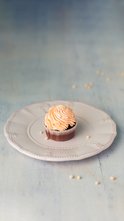 Chocolate cupcake with buttercream frosting on a white plate screenshot