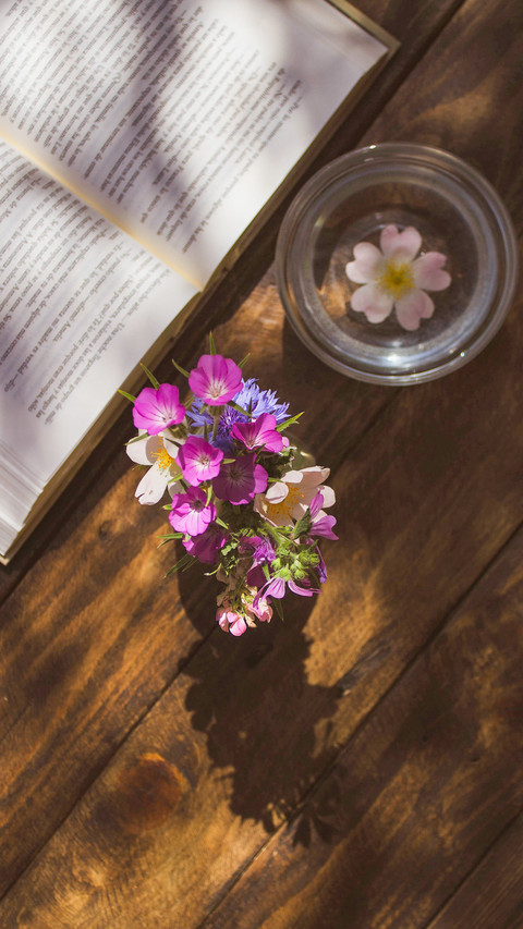 Open book and vase on wooden table screenshot