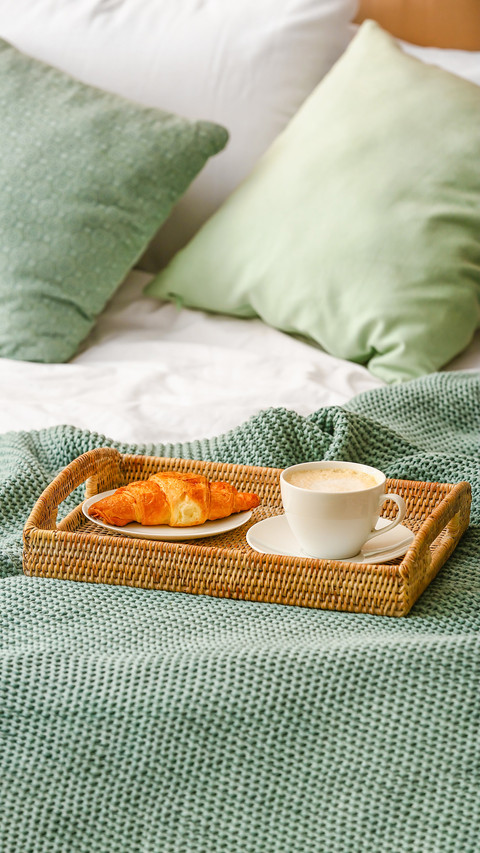Tray with cup of coffee and croissant on bed screenshot