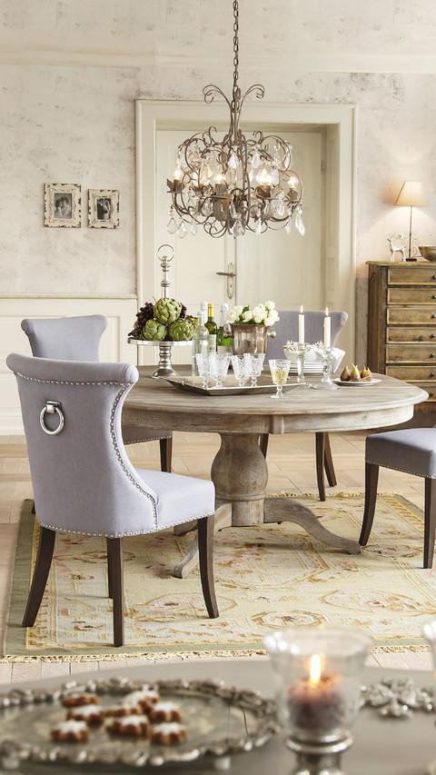 Grey upholstered chairs around silver tray on round screenshot