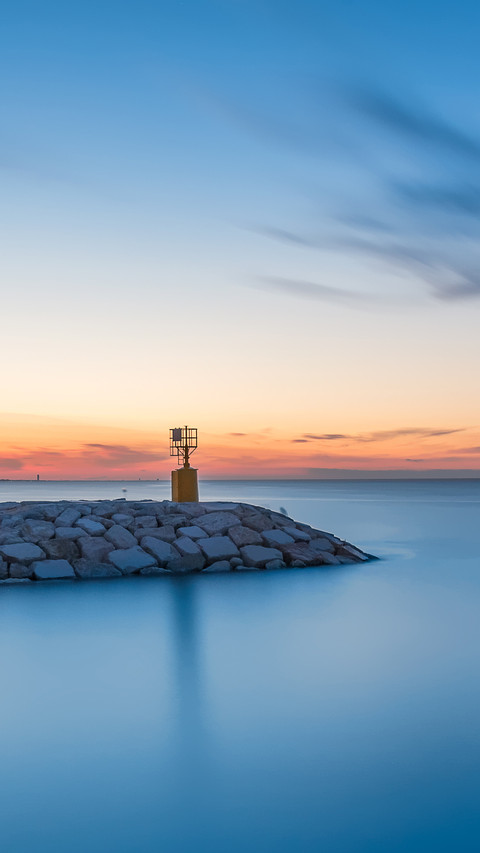 Seascape sunset with rocks and little lighthouse screenshot
