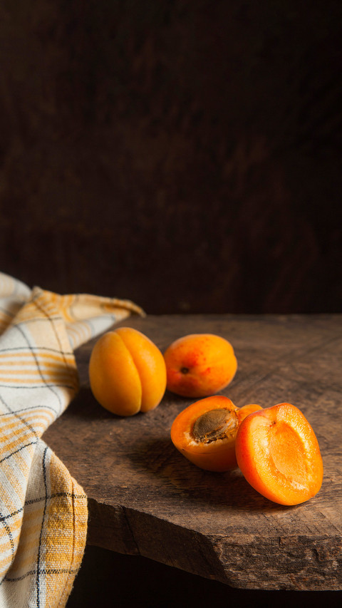 Two whole and half apricots on a vintage wooden background screenshot