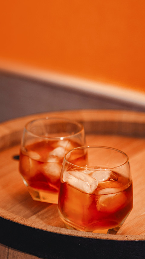 A glass of whiskey with ice on a wooden background screenshot