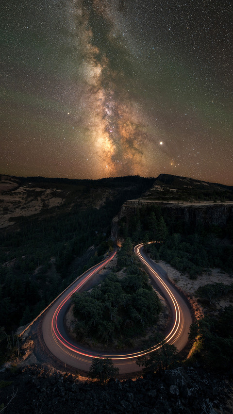 Horseshoe bend road at night with car light streaks screenshot