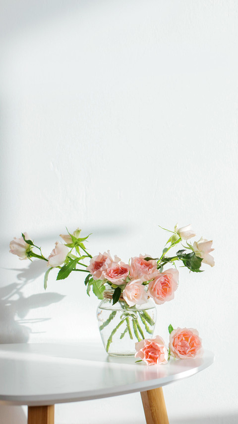 Pink roses in glass jar on white modern table on background screenshot