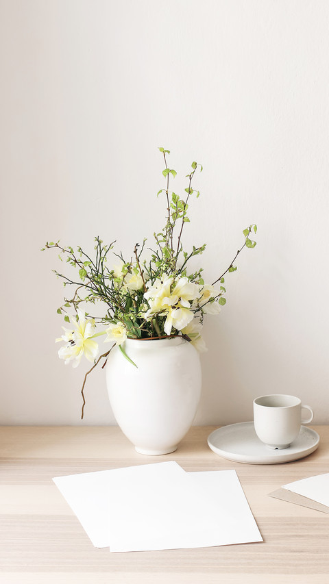 Blueberry branches in ceramic vase pot on wooden table screenshot