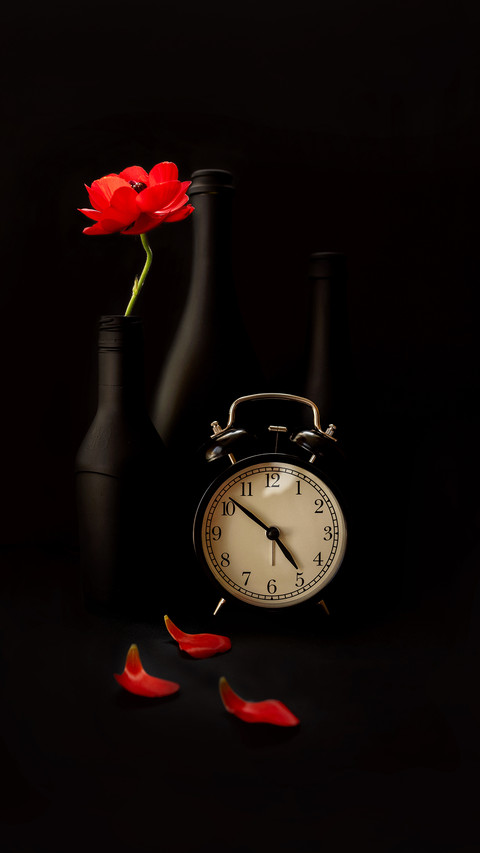 Clock on black background and black bottles and vases screenshot