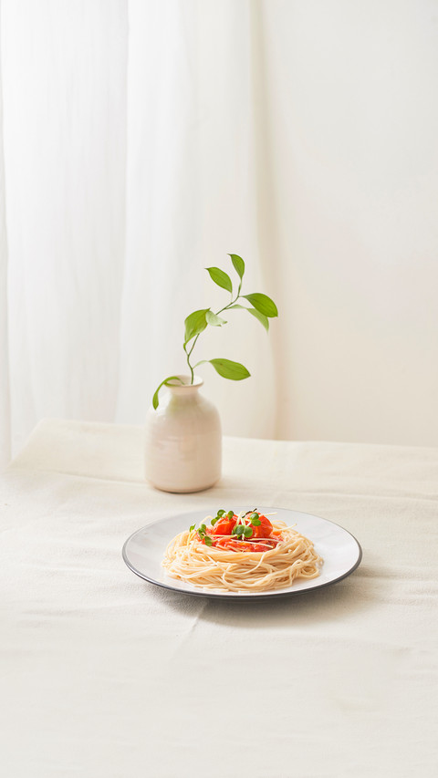 Paghetti bolognese sauce in white dish and a vase of plants screenshot