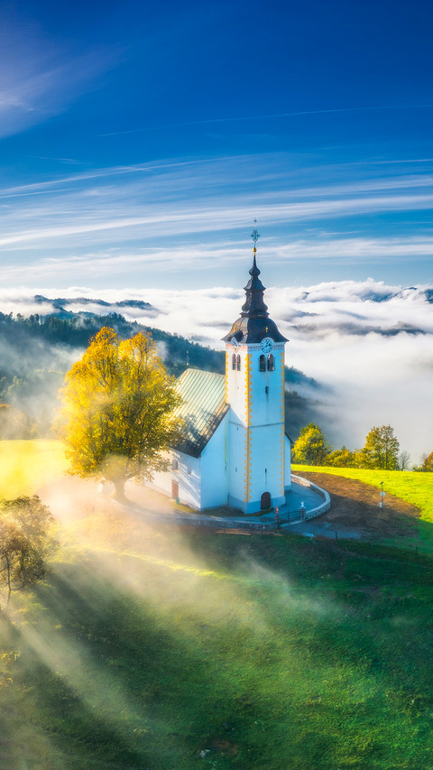 Small church on the hill in low clouds at sunrise screenshot