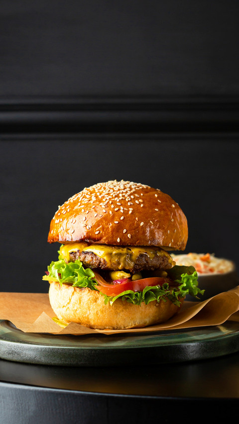 Close up of burger on black table and potato fries screenshot