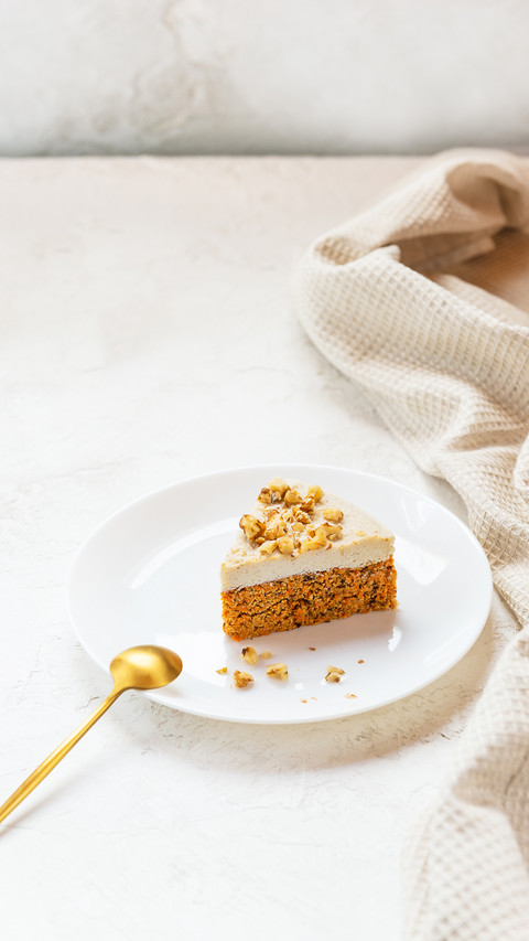 A slice of carrot cake with walnuts on a white plate screenshot