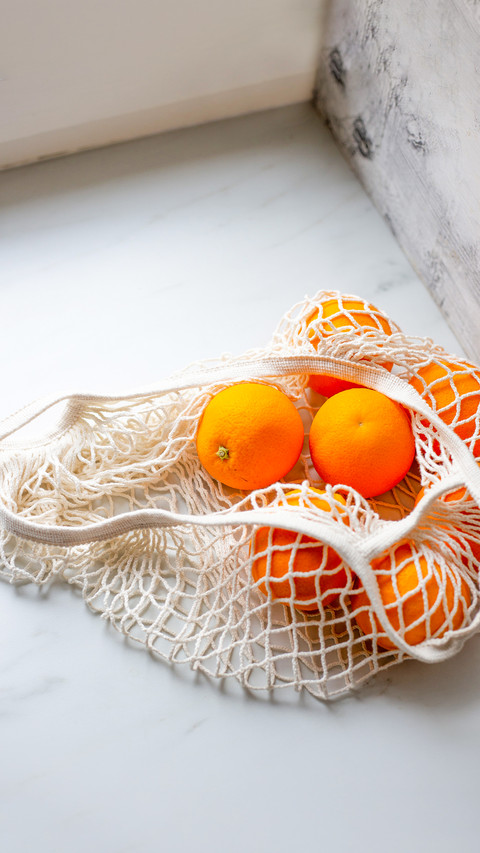 Picked orange fruits in cloth bag on marble background screenshot