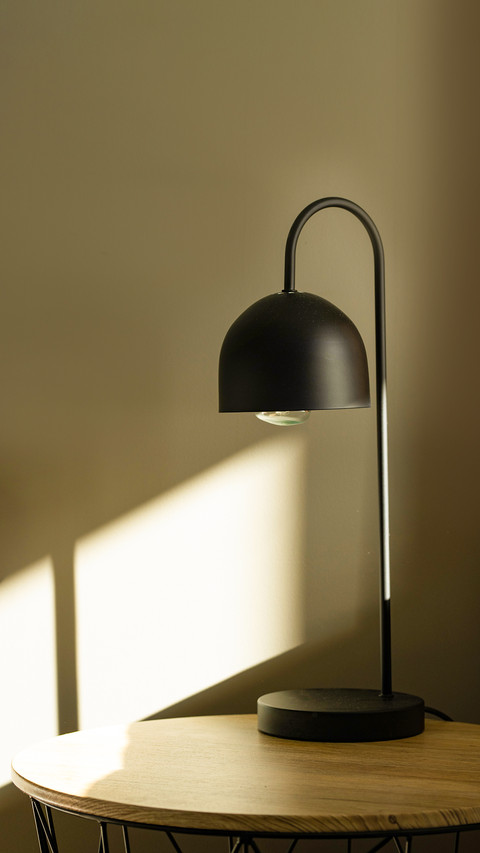 Black lamp on the table with sun light near bed screenshot