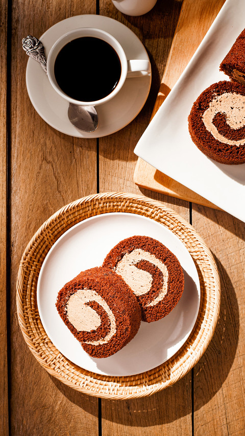Chocolate cake roll with cup of coffee on wooden table screenshot