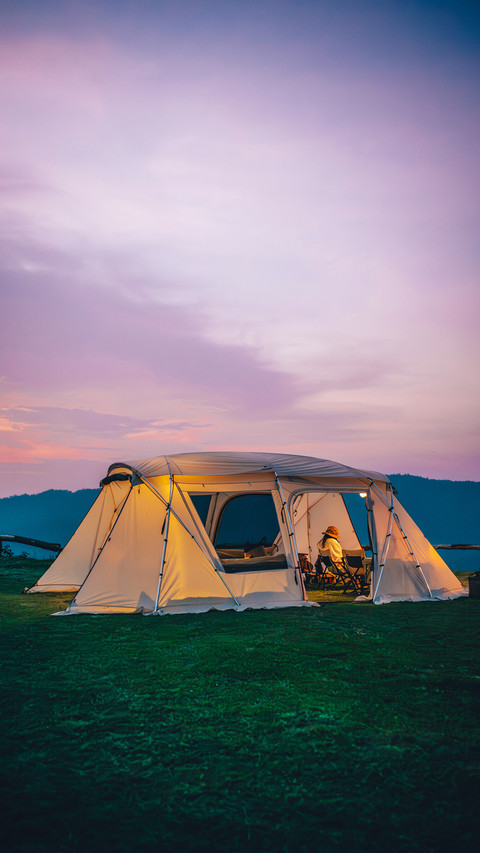 A woman sitting in a white tent during twilight time screenshot
