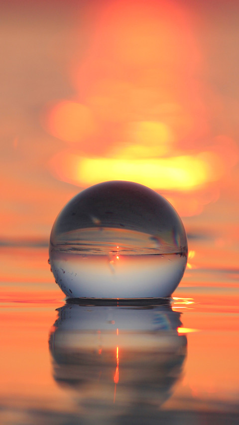 Transparent globe in shallow sea reflecting sunset screenshot
