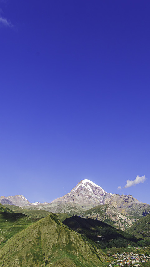 The snow-capped mountains shine against the clear blue sky screenshot