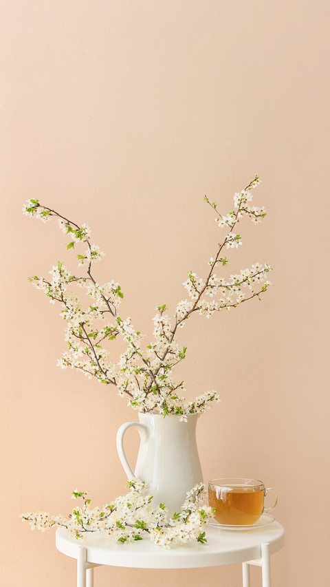 Cup of tasty tea and jug with blooming branches on table screenshot