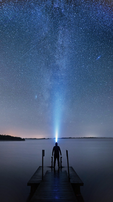 A Man with Flashlight Standing on A Pier by A Lake screenshot