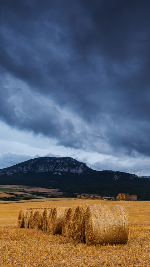 Straw bales in the field at sunset with dramatic sky screenshot