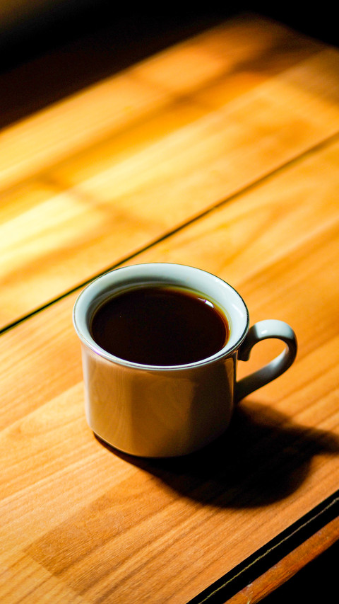 Black coffee in a white cup on a wooden table screenshot