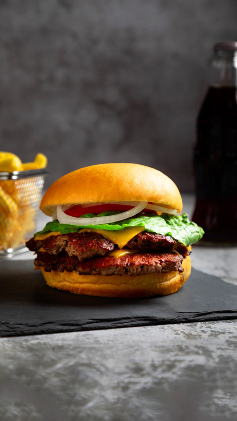 A vertical closeup of a delicious cheeseburger on a table screenshot