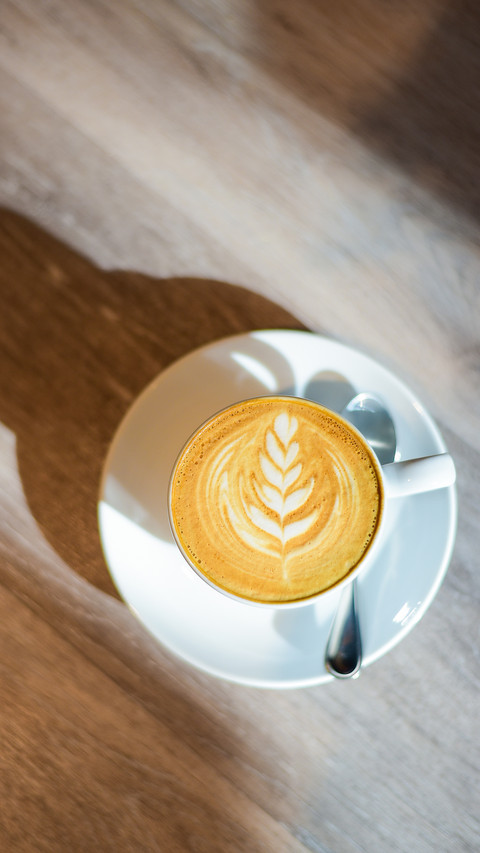 Latte art with sunlight and shadow on wooden background screenshot