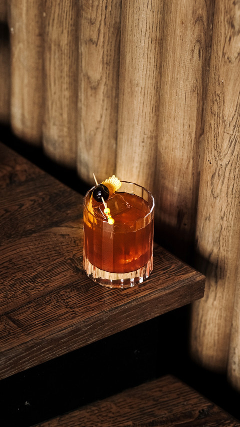 A cocktail with ice and a toothpick with olives screenshot