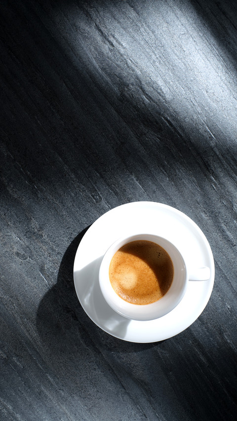 White cup with coffee on a black textured stone table screenshot