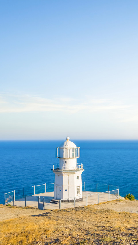 Small white lighthouse on a marine cape screenshot