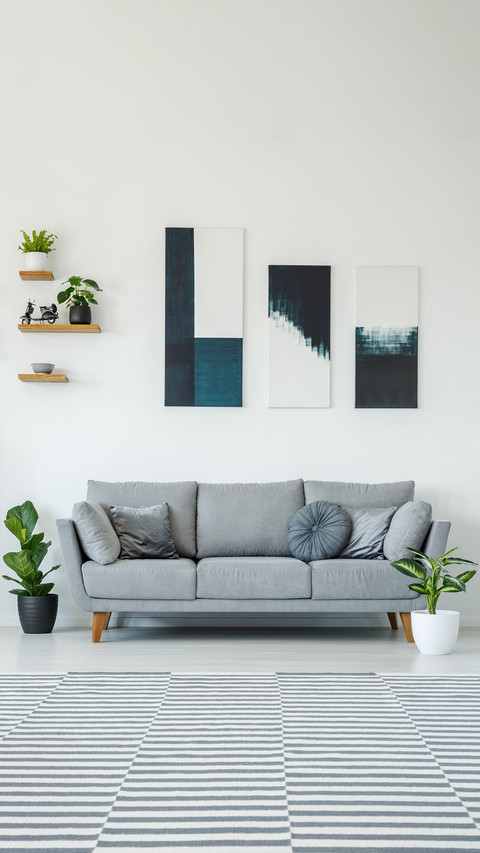 Posters above grey settee in bright living room screenshot