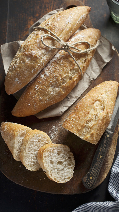 Small baguette rolls whole and sliced on a wooden board screenshot