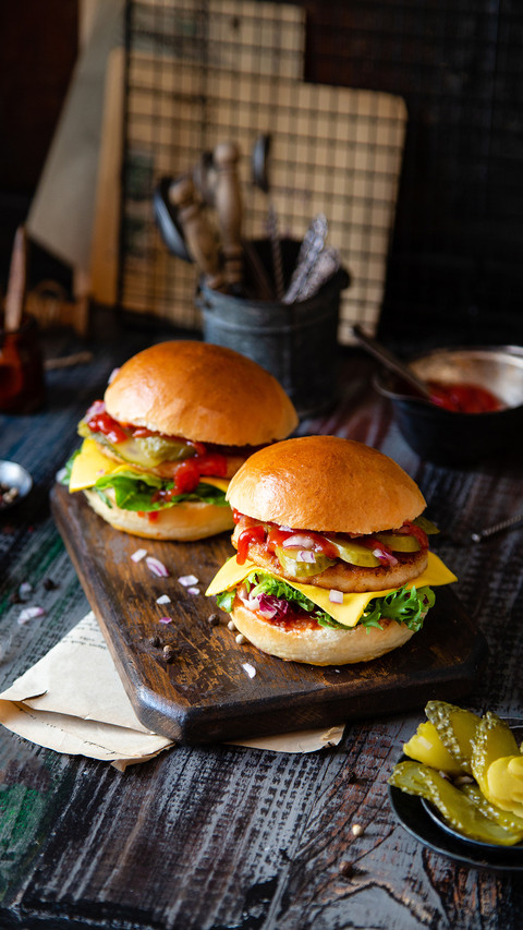 Two homemade burgers with fried chicken on dark wooden table screenshot