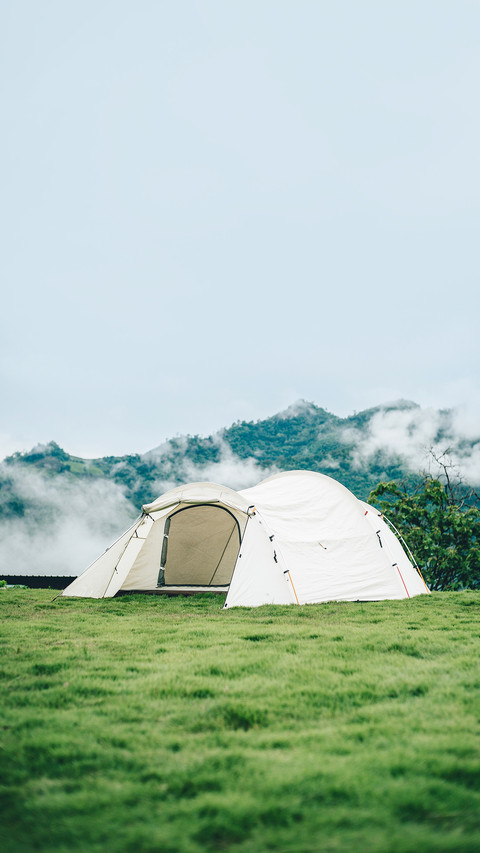 Camping tent in the wilderness on green grass and blue sky screenshot