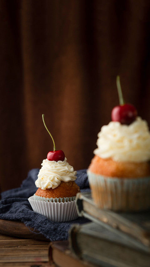 Delicious cupcakes with cream and cherries on top screenshot