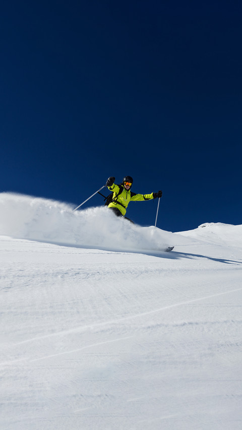 Alpine skier skiing downhill, blue sky on background screenshot