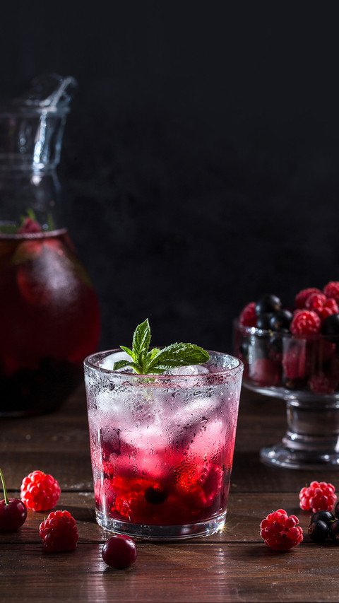 Berry lemonade in a transparent glass on a dark background screenshot