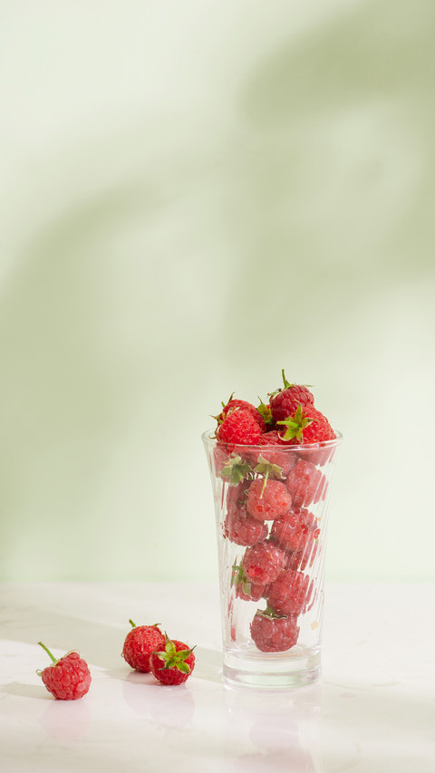 Fresh raspberries in a glass beaker on light background screenshot