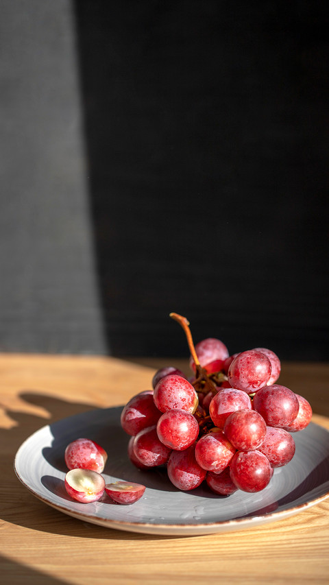 Top view of grapes in gray plate on wooden table screenshot