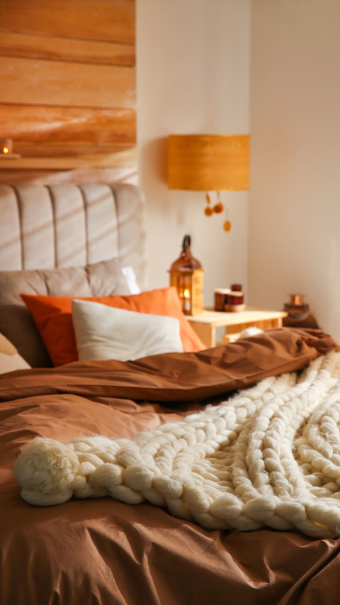 Bed with cozy knitted blanket and cushions indoors screenshot