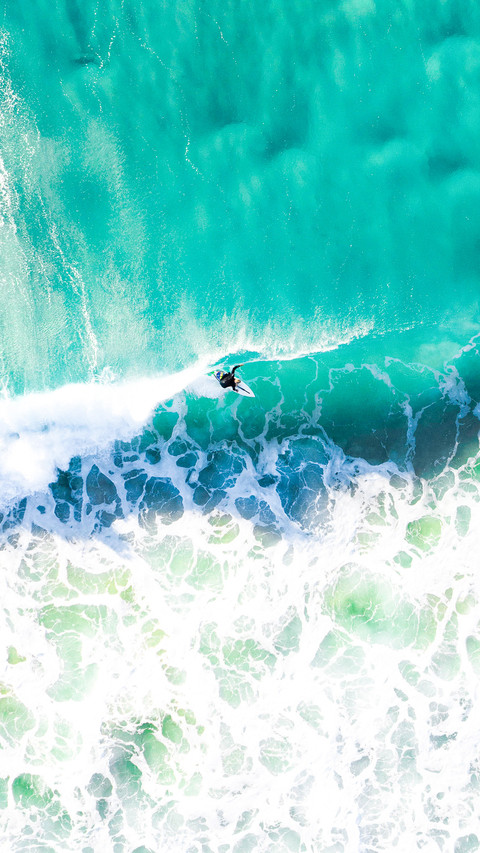 Surfer surfing a wave at sunrise in a blue turquoise ocean screenshot