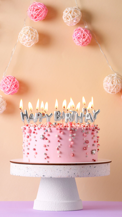 Birthday cake with burning candles on violet table screenshot