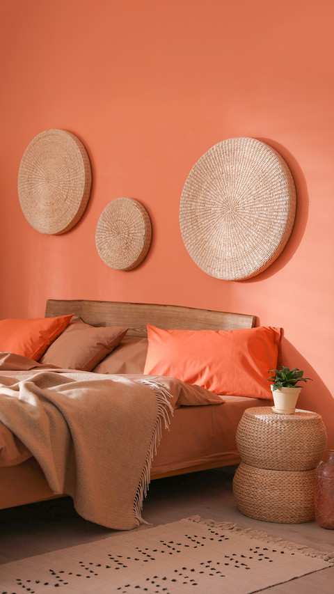 Bed with orange and brown linens in stylish room screenshot
