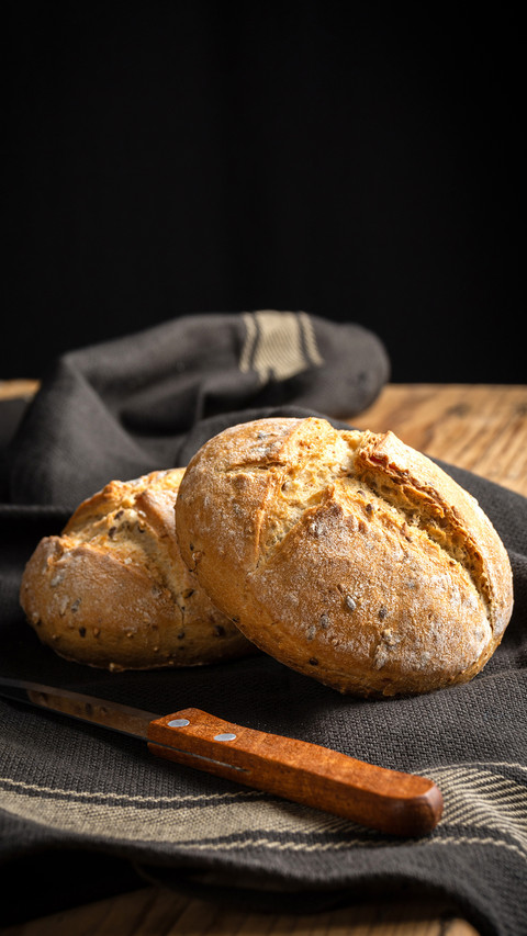 Two quinoa breads on dark cloth with knife on wooden table screenshot