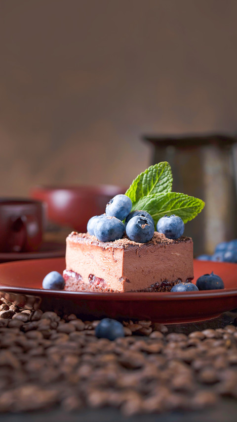 Chocolate cake with blueberries and mint on a brown plate screenshot