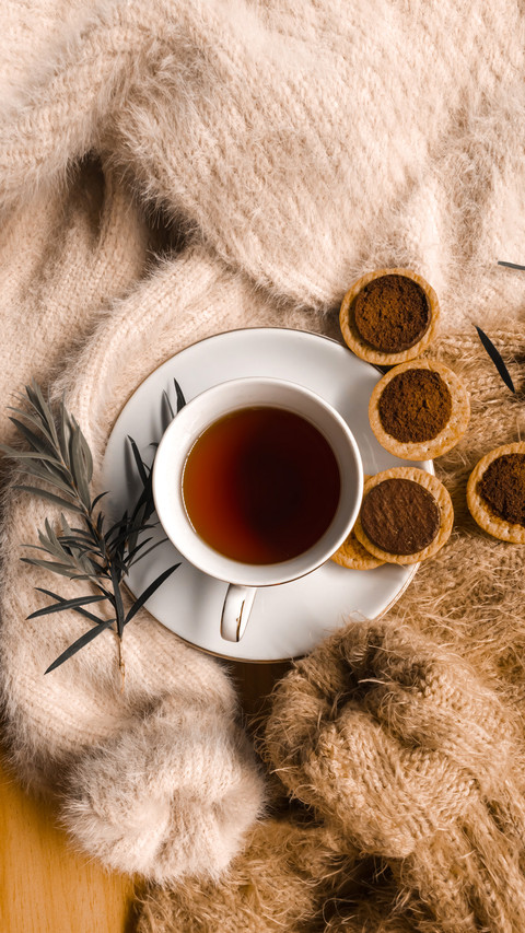 A cup of tea with chopping cookies on piles of sweaters screenshot