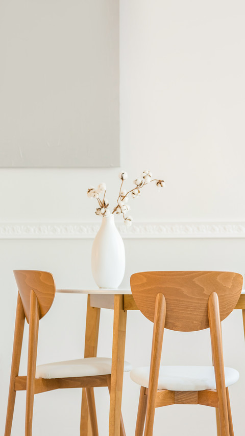 Closeup of flowers in white vase on wooden dining table screenshot